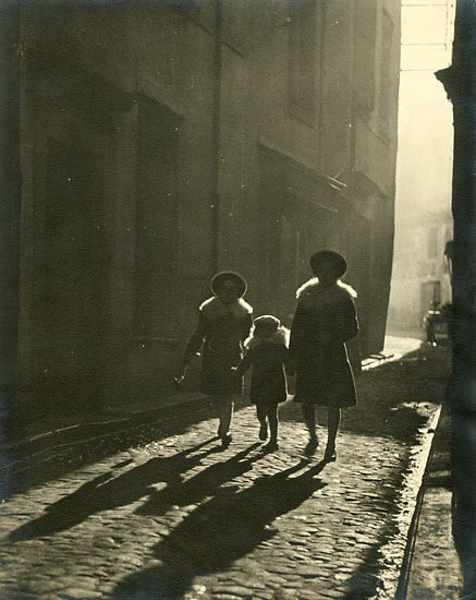 Mother and Children Walking Down Cobblestone Street