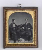Anonymous, British - Two Men at a Table with a Dog at their Feet, One Man Holding a Cased Image