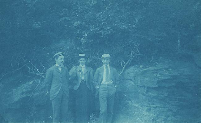 Two Men and a Woman Standing in Front of a Rock Wall